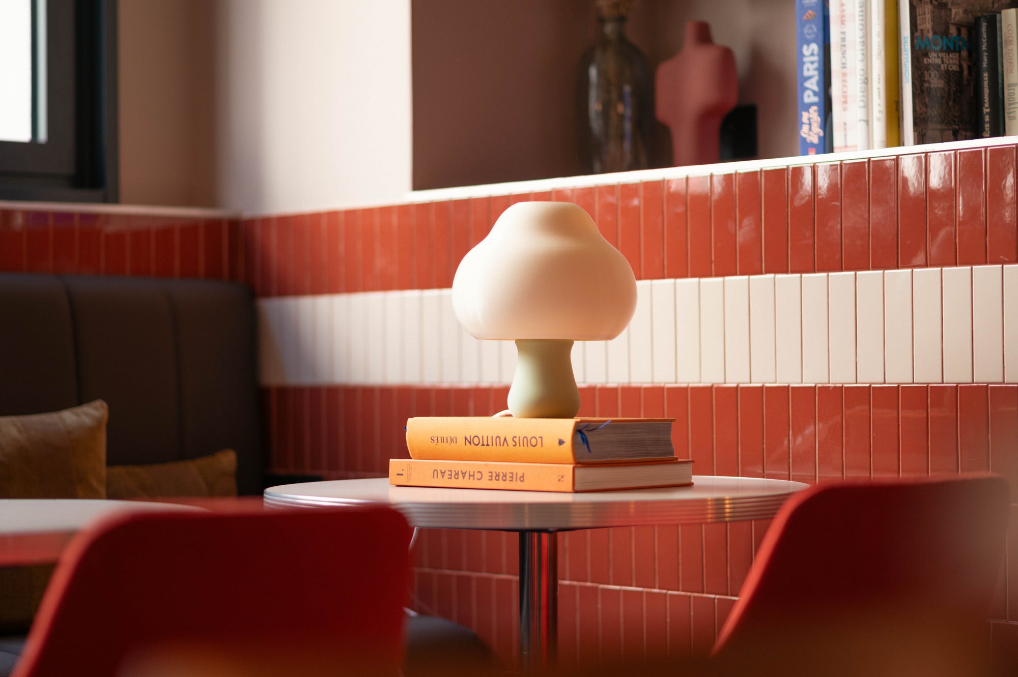 Small lamp on books with a tiled wall and sofa in the background